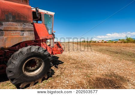 Old burned agriculture combines in a flattened grainfield under a blue sky with white clouds in the countryside of france