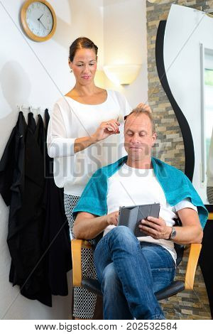 Female Hairdresser Cutting Hair Of Man