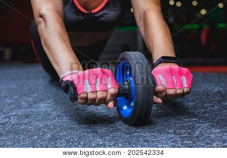Slim bodybuilder girl does the exercises with roller for press in the gym. Sports concept fat burning and a healthy lifestyle.