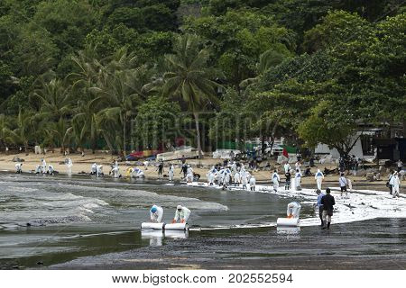 Rayong Thailand - July 31 2013: Workers roll out a ream of absorbent paper for clean-up crude oil spilled at Ao Prao Beach on July 31 2013 in Koh Samet Rayong Thailand.