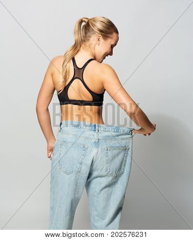 fitness, diet, weight loss and people concept - young slim sporty woman in oversize pants