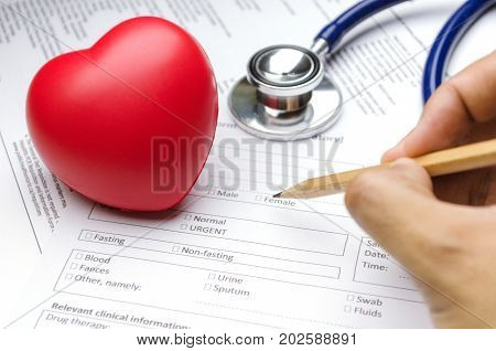 hand writing blank patient information form with stethoscope and red heart on desk healthcare technology medical report record and history patient concept selective focus