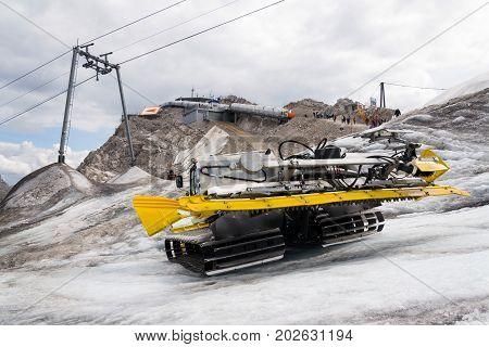 Snow Groomer Snowcat Stands On Dachstein Glacier Near Cable Car