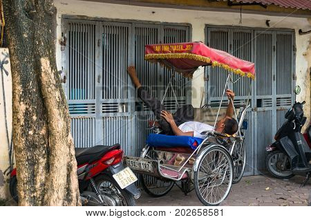 Hanoi Vietnam - August 12 2017: Cyclo bike cab driver sleeping on the street