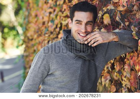 Man Wearing Winter Clothes Smiling In Autumn Leaves Background