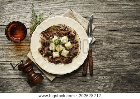 Fresh fried chicken liver with onion and gnocchi on wooden table