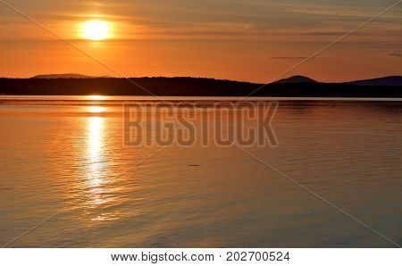 Golden sun sinks over the lake in the evening, golden water, South Ural lake Uvildy