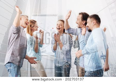 Friendly team. Cheerful group of office workers celebrating a successful project while expressing happiness and resting fter work together