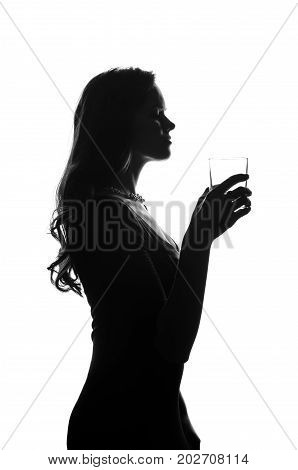 Silhouette of handsome woman with long hair with glass in her hand. She stays side to camera and looks stright. She wears a dress. Police criminal scene in black and white. Studio shot isolated or cutout from background. Studio shot.