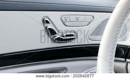 Door handle with Power seat contol buttons of a luxury passenger car. White leather interior of the luxury modern car. Modern car interior details