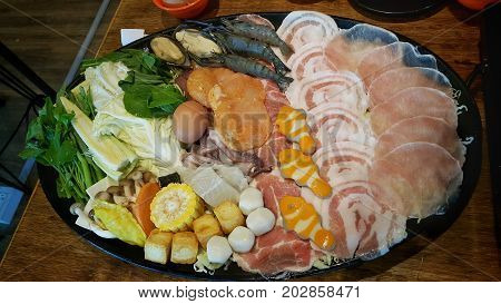 Mixed ingredients on a serving plat including sliced pork , seafood and vegetable for Shabu party.