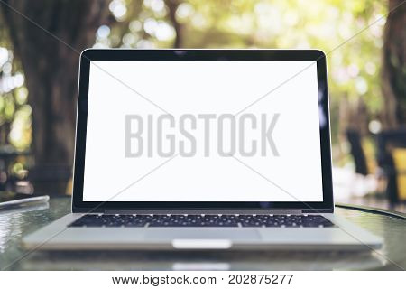 Mockup image of laptop with blank white screen on glass table at outdoor with green nature background