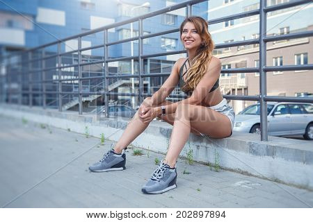 Long Haired Sporty Girl In A Stylish Silver Colored Shorts And Dark Green T-shirt Is Exercising On A