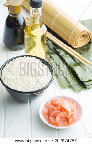 The sushi ingredients on white table. Rice, ginger, soy sauce, vinegar and nori sheets.