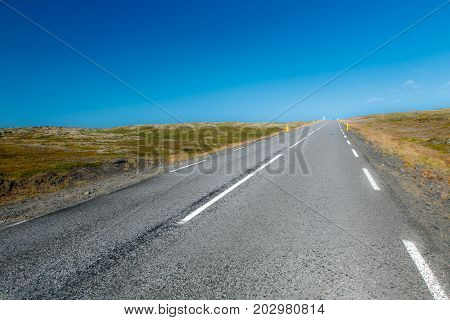 Paved road in Iceland merging with the sky at the horizon.