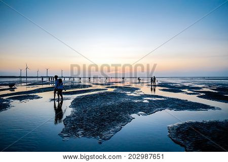 Asia culture - Beautiful landscape of sea level reflect fantasy dramatic sunset sky and people's silhouette in Gaomei wetlands the famous travel attractions in Taichung Taiwan.
