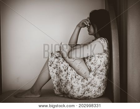 Black and white depressed woman hug her knee and cry while sitting alone. Sad woman concept.