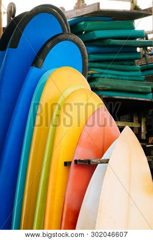 Set Of Multicolored Surf Boards In A Stack By Ocean.bali.indonesia. Surf Boards On Sandy Beach For R