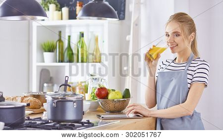 The Girl At The Table In The Kitchen With A Glass Of Orange Jui