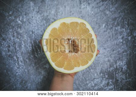 Tropical Summery Fruit Called Pommelo Looking Fresh And Juicy Holding In Hand On The Gray And White 