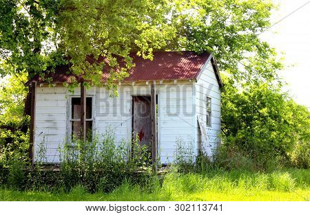 Shabby, Weathered Small House Shack On An Overgrown, Unkempt Lot
