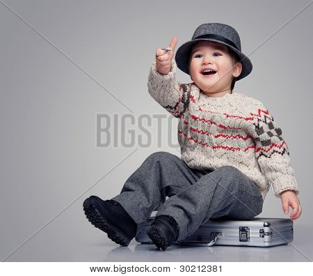 Lächeln Baby Boy sitzt auf einem Koffer.