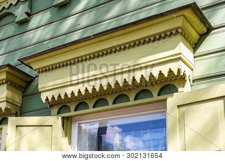 Russian Traditional Wooden Architecture. Facade Of An Old House Decorated With Wooden Carvings, Plat