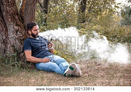 Confident Smoker Smokes Electronic Cigarette Exhales Smoke. Smoking Cessation Tobacco.