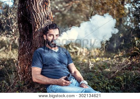 Handsome Vaper Enjoying An Electronic Cigarette. Man Really Likes Process Of Smoking.
