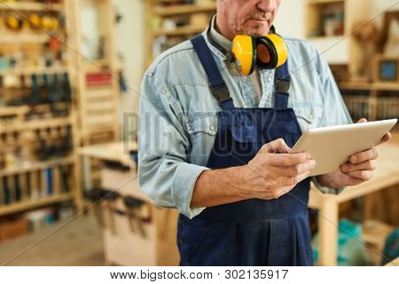 Mid Section Portrait Of Senior Carpenter Using Tablet While Working In Joinery, Copy Space