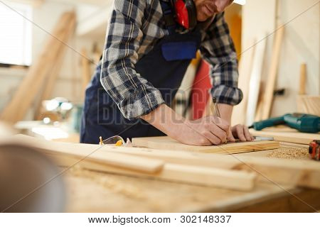 Mid Section Portrait Of Unrecognizable Carpenter Marking Wood While Working In Joinery Lit By Sunlig