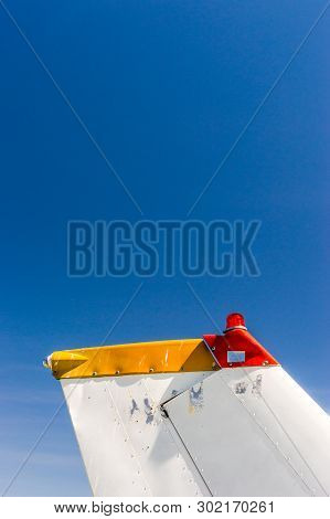 Tail Fin, Rudder And Beacon Lights, Small Single Engine Airplane With Old Paint And Bright Blue Sky.