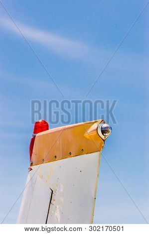 Tail Fin, Rudder And Beacon Lights, Small Single Engine Airplane With Old Paint And Bright Blue Sky.