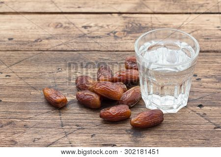 Dried Dates Fruits And A Glass Of Water On A Wooden Table. Traditional Fast Breaking, Muslims Evenin