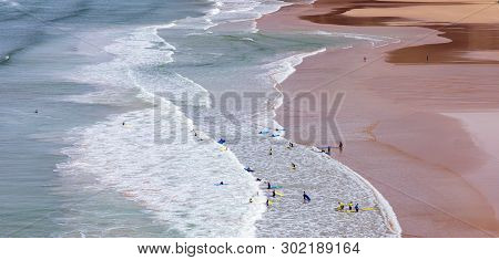 Surfers In The Waves Off Mawgan Porth Beach, Cornwall, Uk