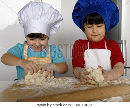 Due bambine cucinare una pizza in una cucina.Ragazzino in una cucina insieme.