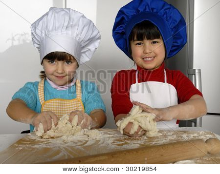 Due bambine cucinare una pizza in una cucina.Ragazzino in una cucina insieme.