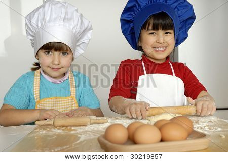 Due bambine cucinare una pizza in una cucina.Ragazzino in una cucina insieme.
