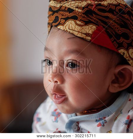 A Portrait Of A 3-month-old Baby Showing A Smile And Wearing Blangkon. Blangkon Is A Typical Head Co