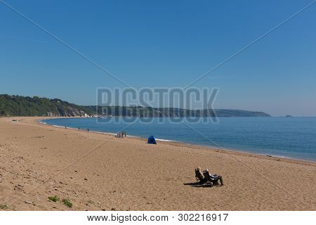 Slapton Sands Beach Devon England Uk With Couple Sitting In Deckchairs