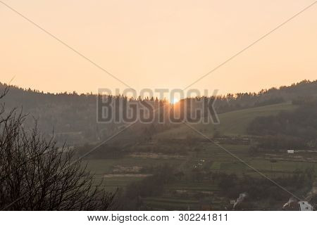 Sunset With Colorful Sky Above Forest In Rural Landscape Witth Fields, Forest And Small Hills Above 