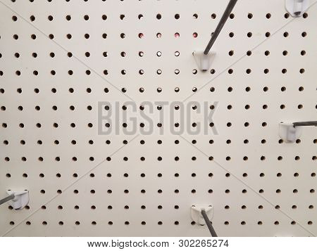 Empty White Pegboard Or Wall With Holes And Metal Hooks
