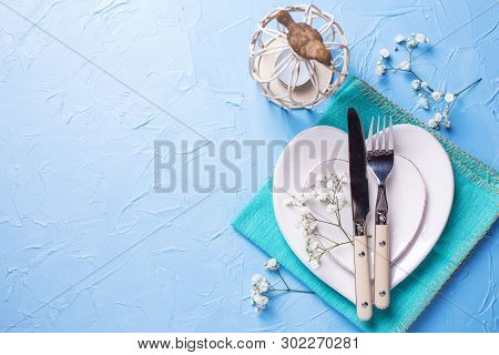 White Plates In Form Of Hearts, Napkin, Knife And Fork And  Fresh White Gypsofila  Flowers On Blue T