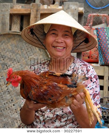 Starší kuřecí dodavatele na Hoi trh, Vietnam.
