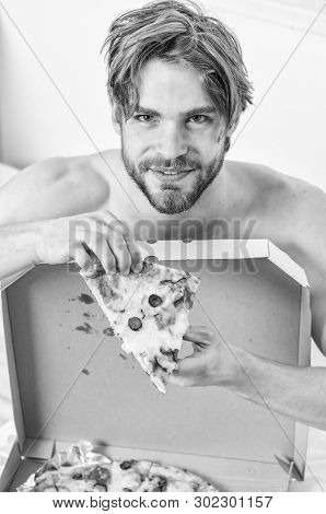 Sexy Man Eat Pizza Lying On Bed. Shirtless Handsome Young Man With Pizza On Bed. Hungry Young Man In