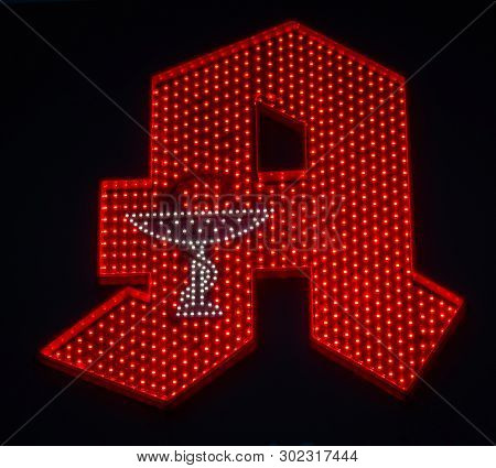 Image Of Red Illuminated German Pharmacy Sign With Dark Background