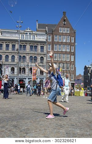 Amsterdam, Netherlands - July 02, 2018: Children Catch Soap Bubbles In The Central Dam Square In Ams
