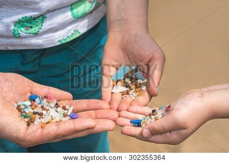 Family Of Mother And Children Holding And Showing Small Tiny Harmful Plastic Beads Collected On The 