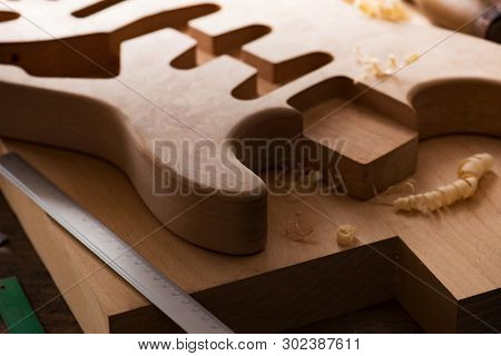 Electric guitar making. Guitar work shop. Unfinished solidbody electric guitar body on work bench. Shallow depth of field.  