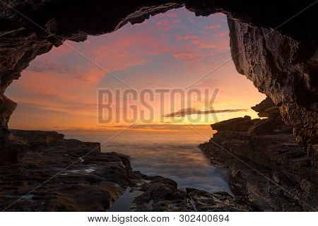 Cave Views Frame A View To A Spectacular Ocean Sunrise Of Yellpws Reds Amd B;ies